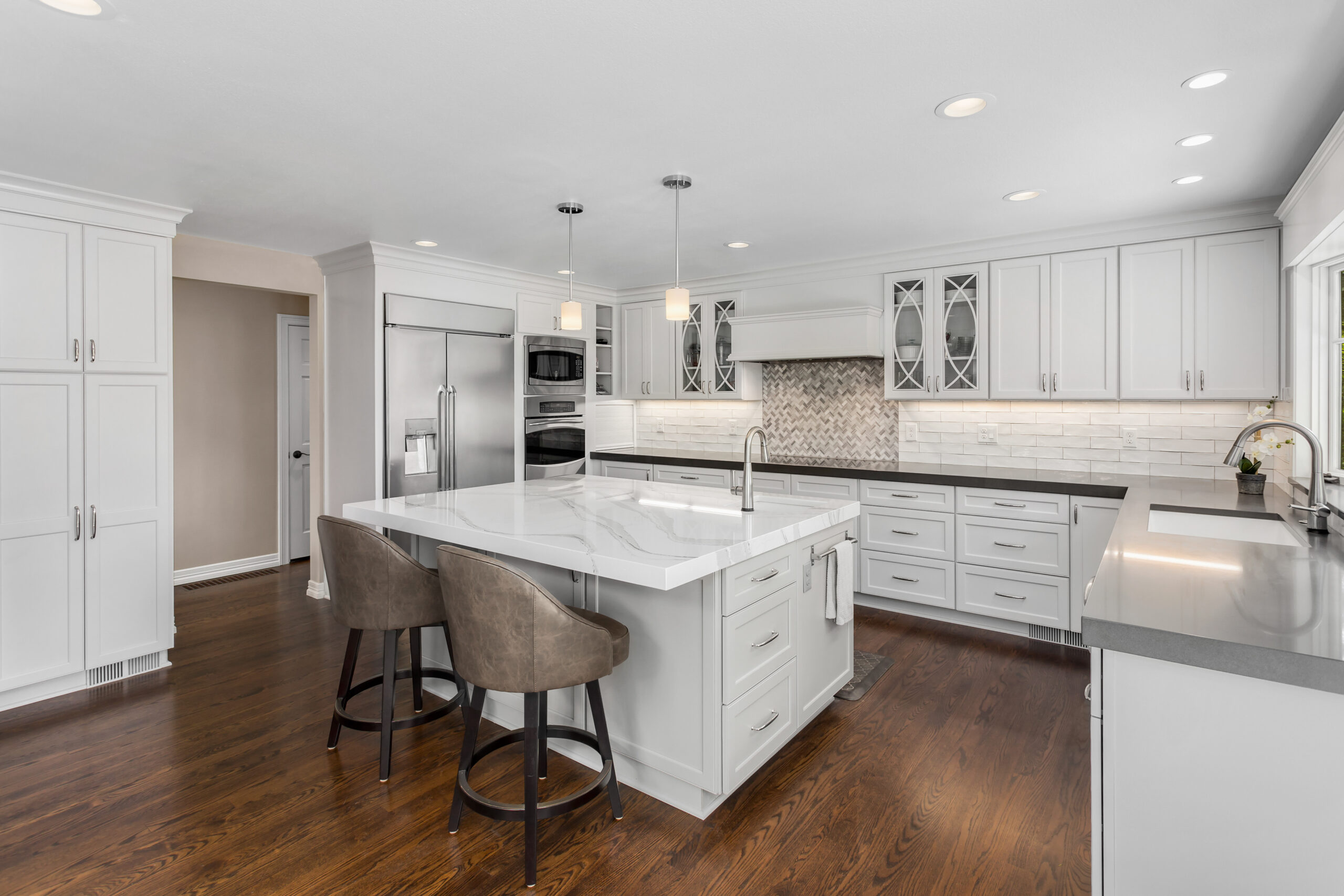 beautiful kitchen in new luxury home with island, pendant lights, oven, range, and hardwood floors.